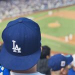 selective focus photography of person wearing LA Dodgers cap looking at field