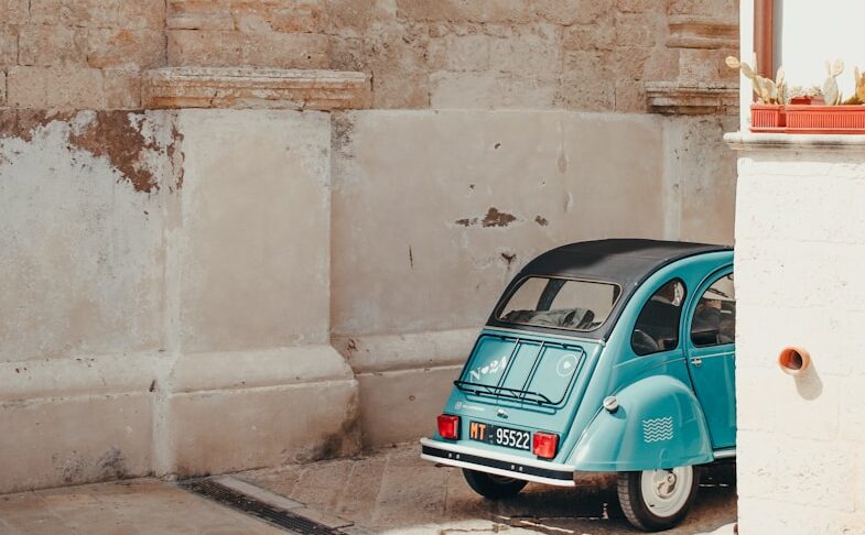 a small blue car parked in front of a building